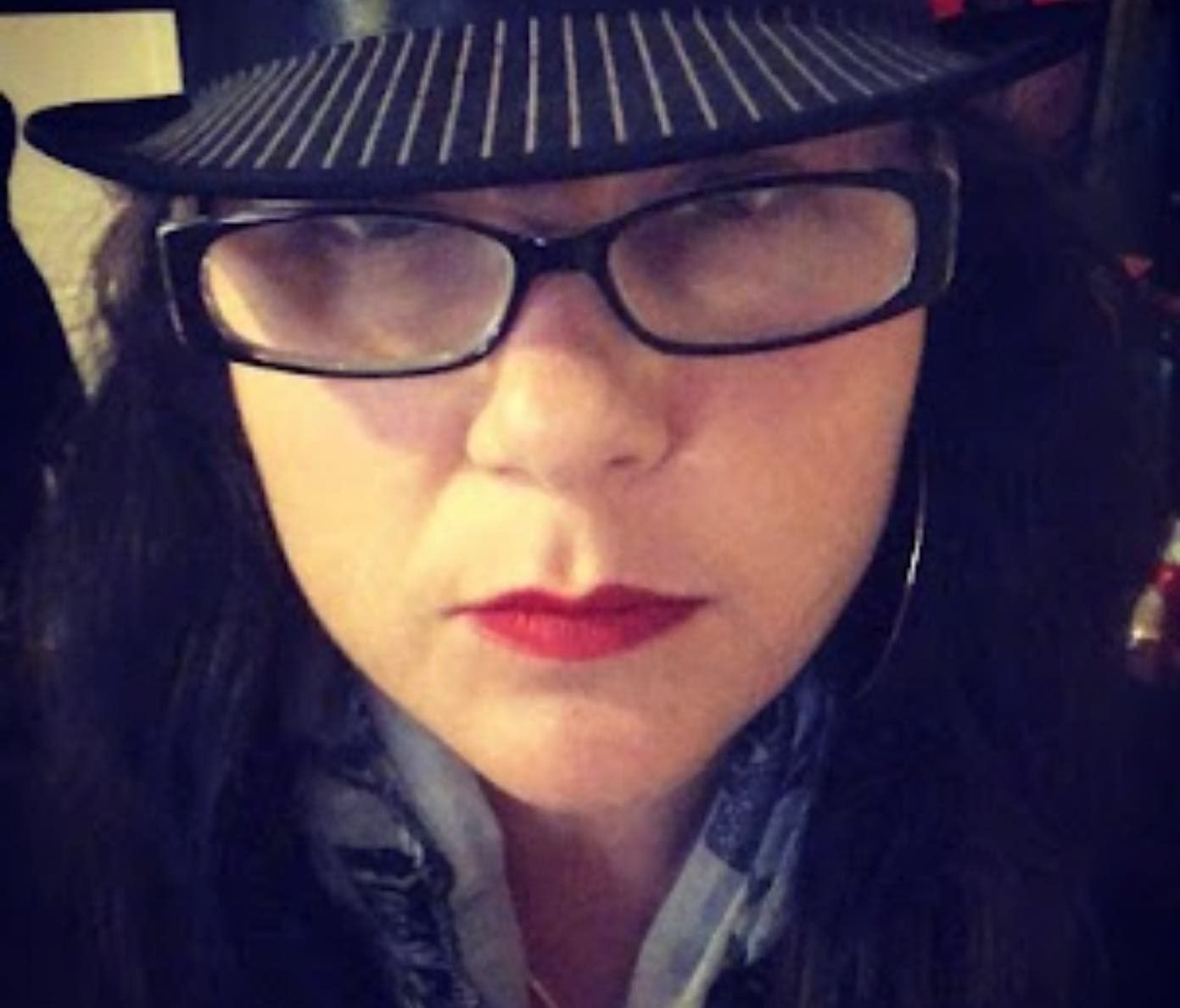 Close-up of Vanessa in a striped hat and glasses, wearing red lipstick